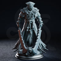 Hooded executioner in layered frayed robes holding two large curved blades, standing over a screaming severed head base, with a ceremonial bell hanging from rope-bound waist. Sculpt by DM Stash.