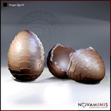 Digital render of Dragon Eggs 03 by Novaminis — two resin dragon egg terrain pieces, one whole and upright with overlapping scales, one cracked open with a jagged broken shell rim and hollow interior visible, shown against a neutral grey background