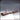 Digital render of Fallen Tree 03 by Novaminis — a long, hollow fallen log with deeply textured bark and multiple clusters of sharp, upward-pointing thorns along its length, shown from a three-quarter front angle in unpainted brown resin tone