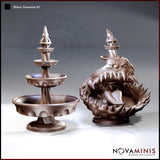 Two resin sculpts side by side: a clean three-tiered stone fountain with finial spire, and a gaping mimic creature with wide fang-lined jaws, lolling tongue, and spine-covered body gripping a basin. Sculpt by Novaminis.