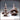 Two resin sculpts side by side: a clean three-tiered stone fountain with finial spire, and a gaping mimic creature with wide fang-lined jaws, lolling tongue, and spine-covered body gripping a basin. Sculpt by Novaminis.