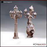 Two Novaminis Mimic Lamppost sculpts side by side: left is a smooth ironwork candelabra lamppost with five lantern arms and spiked finials; right shows the same lamppost with the lower column replaced by a bulging, fanged creature body with wide open jaws.