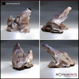 Rock formation with a sharply angled upper spire, layered flanks showing cracked fissures and worn hollows, and a wide irregular base. Four angles showing the full sculptural profile. Sculpt by Novaminis.