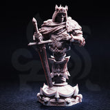 Front view of unpainted grey resin bust of Ridan the Everlasting — skeletal face with hollow eye sockets beneath a spiked crown, armour engraved with heraldic geometric detail, fur-lined cloak, and a large sword resting against the base