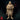 Front-facing render of the Saeth Cromley retired veteran miniature — a heavyset middle-aged man in layered travelling robes and padded armour, holding an open journal in both hands, with a sheathed sword at his belt and a heavy cowl around his shoulders