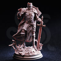 Photograph of printed unpainted grey resin Ser Ludwig miniature — front view showing ornate crusader breastplate with cross motif, flowing cloak, greatsword planted in rubble base with tangled roots, in 32mm scale