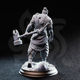 Rear view of the unpainted grey resin Sindan the Southern Hammer miniature, showing the detailed back of his layered robes, rope-wrapped belt, scale armour skirt, and the ornate scrollwork on the head of his maul