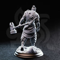 Rear view of the unpainted grey resin Sindan the Southern Hammer miniature, showing the detailed back of his layered robes, rope-wrapped belt, scale armour skirt, and the ornate scrollwork on the head of his maul