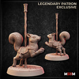 Digital render of two carousel squirrel miniatures by Mia Kay M3DM — one seated holding an acorn with eyes half-closed, one rearing up on hind legs, both mounted on a twisted decorative pole atop acorn-scattered round bases, wearing ornate embroidered saddles with tassels