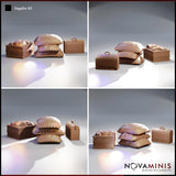 Four-angle digital render of the Novaminis Supplies 03 scatter terrain set showing the stitched sack stack, bread-filled wooden crate, and small domed chest from multiple viewpoints, all unpainted in warm brown clay finish