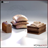 Digital render of the Novaminis Supplies 03 scatter terrain set showing three unpainted resin pieces: a stack of three stitched canvas sacks, a wooden crate filled with bread loaves, and a small domed wooden chest with a handle, all in a warm brown clay colour