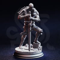 Front view of Plague Carrier 2 — an unpainted grey resin miniature of a muscular skeletal undead warrior in a crouched stance, gripping a broad sword planted in rubble, wearing a single pauldron and tattered chainmail, on a detailed scenic base