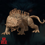 Digital render of the Thorny Vegepygmy miniature from Monster Atlas, shown in a three-quarter front view. The creature crouches on four clawed feet with a hooked tail raised behind it. Its back is lined with tall fleshy finger-like stalks, and its warty, pockmarked hide is covered in bony nodules and spines. The face features small beady eyes, jutting protrusions, and dangling tendrils.