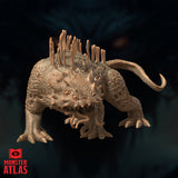 Digital render of the Thorny Vegepygmy miniature by Monster Atlas, viewed from a front-facing low angle. The creature faces the viewer with its knot of small eyes, frilled spiny jaw, and dangling facial tendrils clearly visible. The fleshy dorsal stalks rise prominently above its broad hunched body and the hooked tail curves up behind.