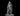 Grey resin digital render of a tiefling male sorcerer miniature at 32mm scale, posed confidently in a tailored suit and sweeping cloak, one hand tipping the brim of a wide horned witch's hat, the other gripping a tall topped staff. The figure stands on a flat round base against a black background.