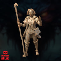 Second front-facing unpainted resin render of Vajra Safahr female wizard miniature showing the same pose — skull-cluster staff raised in left hand, right hand extended mid-cast, structured coat with piped trim, 32mm scale by Monster Atlas