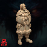 Unpainted resin miniature of Vellyne Harpell frost wizard, three-quarter side view — showing large travel satchel slung at her side, buckled belt pouch, and concealed blade at her hip, fur-hemmed robes and fur-lined capelet clearly visible