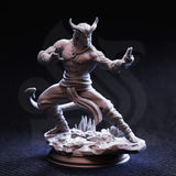Front view of an unpainted grey resin miniature of Verek Heartless, a tiefling monk with swept horns and arcane tattoos on his forearm, posed in a low martial stance with hands open and tail curling at his side, mounted on a detailed shattered-stone scenic base