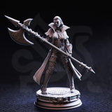 Front-angle photograph of unpainted grey resin Vika 'Doll Lips' half-orc interrogator miniature — confident wide stance, engraved halberd raised diagonally, high-collared coat, detailed armour plating, on an ornate round display base