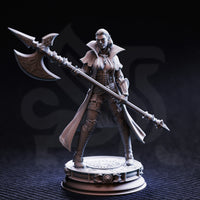 Front-angle photograph of unpainted grey resin Vika 'Doll Lips' half-orc interrogator miniature — confident wide stance, engraved halberd raised diagonally, high-collared coat, detailed armour plating, on an ornate round display base