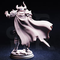 Photograph of Vilnais the Ashen unpainted grey resin miniature from behind — showcasing the extraordinary texture detail of the woven fabric cape sweeping to one side, both arms outstretched, spiked pauldrons visible over the shoulders.