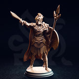Unpainted resin miniature of Vilryn Kaedrys Sun Elf Gladiator, front view — showing sun-disc breastplate, segmented armour, studded war-skirt, sweeping cloak, trident polearm, round shield, and extended sword, on a cobblestone round base