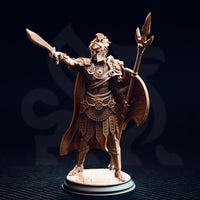 Unpainted resin miniature of Vilryn Kaedrys Sun Elf Gladiator, front view — showing sun-disc breastplate, segmented armour, studded war-skirt, sweeping cloak, trident polearm, round shield, and extended sword, on a cobblestone round base