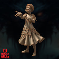 Female mage with natural curly hair and round glasses, both arms raised and fingers spread wide as though directing arcane energy. Layered diamond-patterned coat with flared skirt. Sculpt by Monster Atlas.
