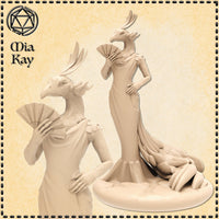 Unpainted resin miniature of a peacock birdfolk lady at 32mm scale, shown in two views. She wears a flowing gown with a feathered peacock-plume train spread across the base, holds a decorative fan close to her beak, and rests her free hand on her hip in a poised, confident stance. Her crest features upswept avian feathers. Sculpted by Mia Kay M3DM.
