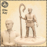 Unpainted resin miniature of a halfling shepherd at 32mm scale, sculpted by Mia Kay M3DM. The figure stands upright holding a tall wooden crook in his right hand, wearing a cross-laced leather tunic, buckled belt, and fur-trimmed boots. His pointed ears and sharp expression convey quiet determination. Shown against a parchment-style background with a close-up bust detail inset to the left.