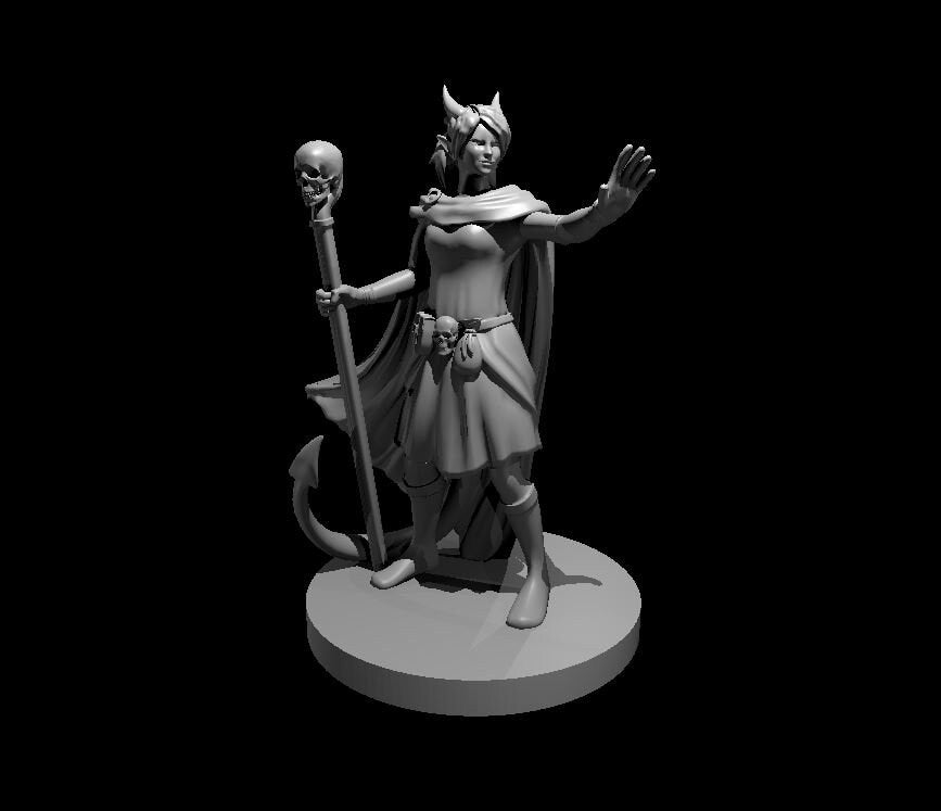 Unpainted grey resin digital render of a female tiefling warlock miniature at 32mm scale. She stands in a confident pose with small horns, pointed ears, and a tail curling behind her. Her right hand grips a tall staff topped with a human skull, and a second small skull hangs from her belt. Her left arm is raised with an open palm as if casting a spell or issuing a warning. She wears a flowing cape, a short dress, and knee-high boots, and stands on a flat round base.