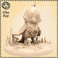 Unpainted resin miniature of a chibi baby phoenix, sculpted by Mia Kay M3DM — a small round-headed bird creature with a flame crest, wide hollow eyes, layered feather-like body, large taloned feet, and a short flared tail, posed mid-strut on a jagged rocky base with stone spurs, shown as a digital render in a warm beige tone