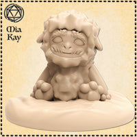 Digital render of a Baby Yeti miniature by Mia Kay M3DM — a squat, round-bodied creature with thick shaggy fur, stubby clawed paws planted wide, a tufted brow, and a wide vacant grin with pale blank eyes, seated on an oval scenic snow base, shown in unpainted tan resin