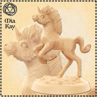 Unpainted cream resin miniature of a Baby Kirin — a rearing foal with scaled markings on a rocky base, beside the large sculpted head of an elder kirin with a mane and dragon-like features. Digital render by Mia Kay M3DM.