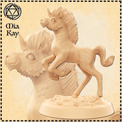 Unpainted cream resin miniature of a Baby Kirin — a rearing foal with scaled markings on a rocky base, beside the large sculpted head of an elder kirin with a mane and dragon-like features. Digital render by Mia Kay M3DM.