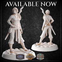Front and rear views of an unpainted female elf monk miniature by M3DM, showing flowing sash details, spiral rune tattoos on her torso, and a twisted flame-topped staff across her back, on a cobblestone base