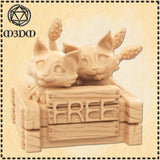 Digital render of two displacer beast kittens in an unpainted resin beige colourway, both cubs peering over the top of a rough wooden crate with a carved 'FREE' sign on the front. Each kitten has six legs and two club-tipped tentacles rising behind them.