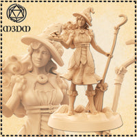 Unpainted beige resin render of the Dessert Witch miniature by Mia Kay M3DM — a female witch in a wide-brimmed hat standing on a pumpkin base, holding a plate of iced biscuits in one hand and a hooked staff in the other, with a ribbon-tied broomstick beside her and a donut brooch at her collar