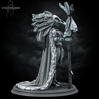 Orc shaman miniature with a towering feathered headdress and bone staff, wearing a fur-trimmed wrap and skull ornaments, standing on a textured scenic base. Sculpted by Stormborn Collectibles.